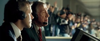 Movie still from “Goal! The Dream Begins” (2005), directed by Michael Winterbottom – A man in a suit and tie wearing a headset; Close Up shot, Low angle