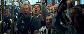 Movie still from “Goal! The Dream Begins” (2005), directed by Michael Winterbottom – A group of men in a crowd of people cheering; Medium shot, High angle