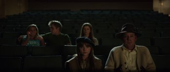A woman in a hat is sitting in a movie theater
