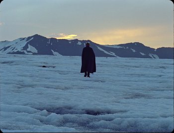 A person in a cape standing in the snow
