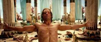 Movie still from “Gods of Egypt” (2016), directed by Alex Proyas – A man with his arms outstretched in an egyptian setting; Medium shot, Low angle