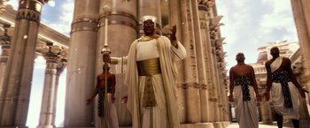 Movie still from “Gods of Egypt” (2016), directed by Alex Proyas – A man dressed as a pharaoh standing in front of a building; Wide shot, Low angle