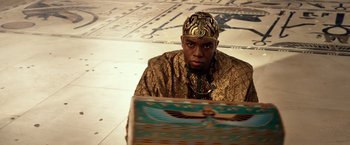 Movie still from “Gods of Egypt” (2016), directed by Alex Proyas – A man wearing a gold crown and a gold robe; Medium shot, Over the shoulder angle
