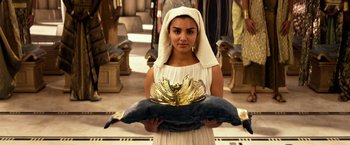 Movie still from “Gods of Egypt” (2016), directed by Alex Proyas – A woman in a white dress holding a gold bowl; Medium shot, Overhead angle