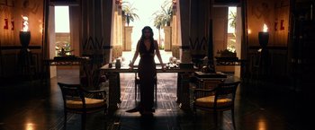 Movie still from “Gods of Egypt” (2016), directed by Alex Proyas – A woman standing at a table in front of an open door; Wide shot, High angle