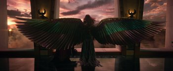 Movie still from “Gods of Egypt” (2016), directed by Alex Proyas – A person with a large wing standing in front of a window; Wide shot, Low angle