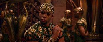Movie still from “Gods of Egypt” (2016), directed by Alex Proyas – A man in a gold and green outfit with a gold crown; Close Up shot, Over the shoulder angle