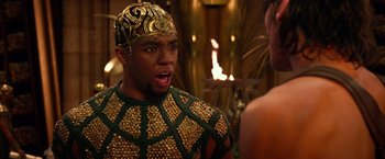 Movie still from “Gods of Egypt” (2016), directed by Alex Proyas – A man wearing a gold and black costume and a gold crown; Close Up shot, Over the shoulder angle