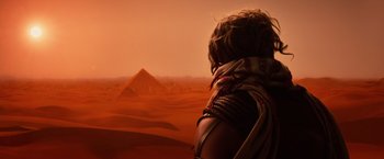 Movie still from “Gods of Egypt” (2016), directed by Alex Proyas – A woman standing in front of a pyramid in the desert; Wide shot, Over the shoulder angle