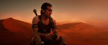 Movie still from “Gods of Egypt” (2016), directed by Alex Proyas – A man sitting on the ground with a sword in his hand; Medium shot, Over the shoulder angle