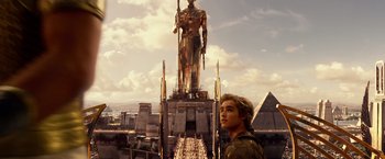 Movie still from “Gods of Egypt” (2016), directed by Alex Proyas – A man standing in front of a large statue of a man in a suit; Extreme Wide shot, Low angle