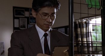 Movie still from “Godzilla vs. Destoroyah” (1995), directed by Ishirô Honda – A man in a suit and tie looking at a tablet; Close Up shot, Low angle