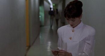 Movie still from “Godzilla vs. Destoroyah” (1995), directed by Ishirô Honda – A woman in a white uniform looking at her cell phone; Close Up shot, Over the shoulder angle