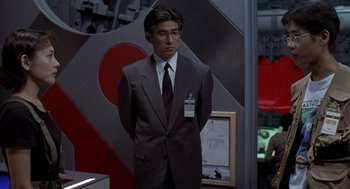 Movie still from “Godzilla vs. Destoroyah” (1995), directed by Ishirô Honda – A man in a suit and tie standing in front of a wall; Medium shot, Low angle