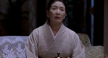 Movie still from “Godzilla vs. Destoroyah” (1995), directed by Ishirô Honda – An asian woman wearing a white robe holding a tea pot; Close Up shot, Low angle