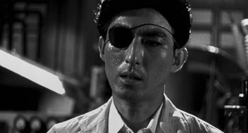 Movie still from “Godzilla vs. Destoroyah” (1995), directed by Ishirô Honda – A black and white photo of a man wearing a pirate eye patch; Close Up shot, Low angle