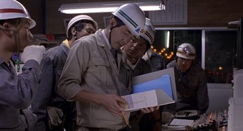 Movie still from “Godzilla vs. Destoroyah” (1995), directed by Ishirô Honda – A group of men standing next to each other in a room; Medium shot, Over the shoulder angle