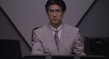 Movie still from “Godzilla vs. Destoroyah” (1995), directed by Ishirô Honda – A man wearing a suit and tie sitting in a chair; Close Up shot, Low angle