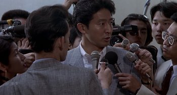 Movie still from “Godzilla vs. Destoroyah” (1995), directed by Ishirô Honda – A group of men holding microphones in front of a camera; Close Up shot, Over the shoulder angle
