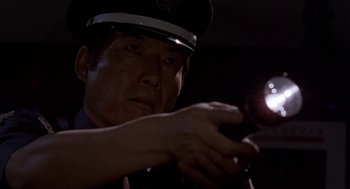 Movie still from “Godzilla vs. Destoroyah” (1995), directed by Ishirô Honda – A man in a police uniform holding a cell phone; Close Up shot, Low angle