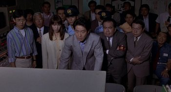 Movie still from “Godzilla vs. Destoroyah” (1995), directed by Ishirô Honda – A group of people standing around a computer screen; Medium shot, High angle