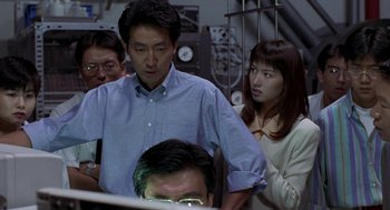 Movie still from “Godzilla vs. Destoroyah” (1995), directed by Ishirô Honda – A group of people standing next to each other in front of a computer; Medium shot, Low angle
