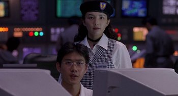 Movie still from “Godzilla vs. Destoroyah” (1995), directed by Ishirô Honda – A man and a woman are looking at a computer screen; Medium shot, Low angle