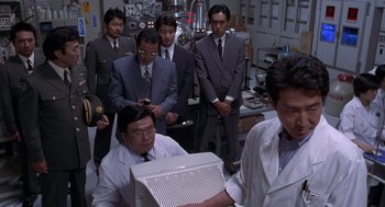 Movie still from “Godzilla vs. Destoroyah” (1995), directed by Ishirô Honda – A group of people in a lab looking at a computer screen; Medium shot, Low angle