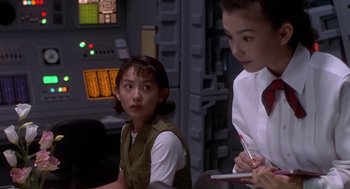 Movie still from “Godzilla vs. Destoroyah” (1995), directed by Ishirô Honda – A woman sitting next to another woman holding a pen; Medium shot, Over the shoulder angle