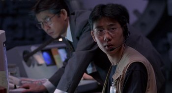 Movie still from “Godzilla vs. Destoroyah” (1995), directed by Ishirô Honda – A man with a headset is sitting in front of another man; Close Up shot, High angle