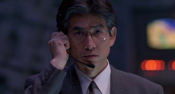 Movie still from “Godzilla vs. Destoroyah” (1995), directed by Ishirô Honda – A man in a suit and tie holding a headset; Close Up shot, Low angle