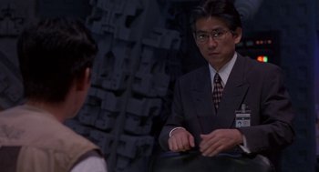 Movie still from “Godzilla vs. Destoroyah” (1995), directed by Ishirô Honda – A man in a suit and tie sitting in front of another man; Medium shot, Over the shoulder angle