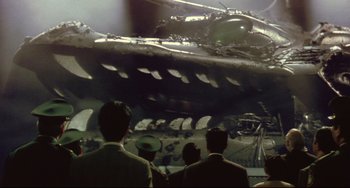 Movie still from “Godzilla vs. Mechagodzilla II” (1993), directed by Kazuki Ômori – A group of people standing in front of a tank; Extreme Wide shot, Low angle