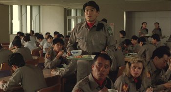 Movie still from “Godzilla vs. Mechagodzilla II” (1993), directed by Kazuki Ômori – A group of young men eating food in a room; Medium shot, Low angle