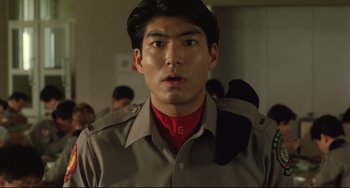 Movie still from “Godzilla vs. Mechagodzilla II” (1993), directed by Kazuki Ômori – A man in a brown shirt is looking at the camera; Close Up shot, Low angle
