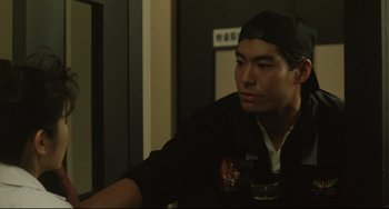 Movie still from “Godzilla vs. Mechagodzilla II” (1993), directed by Kazuki Ômori – A man sitting in front of a wall with a cup; Close Up shot, Over the shoulder angle