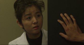 Movie still from “Godzilla vs. Mechagodzilla II” (1993), directed by Kazuki Ômori – A woman in a white lab coat looking at a wall; Close Up shot, Low angle