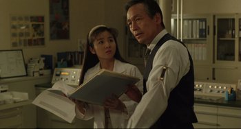 Movie still from “Godzilla vs. Mechagodzilla II” (1993), directed by Kazuki Ômori – A man and a woman standing next to each other holding papers; Medium shot, Low angle