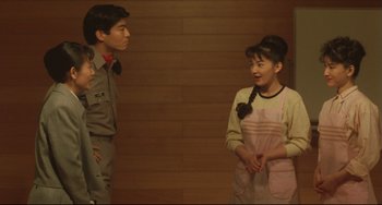 Movie still from “Godzilla vs. Mechagodzilla II” (1993), directed by Kazuki Ômori – Two young people standing next to each other in front of a wooden wall; Medium shot, Over the shoulder angle