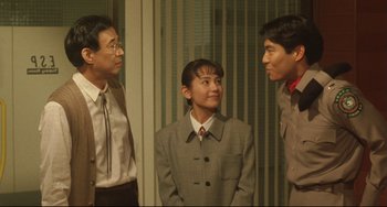 Movie still from “Godzilla vs. Mechagodzilla II” (1993), directed by Kazuki Ômori – A group of people standing next to each other in a room; Medium shot, Over the shoulder angle