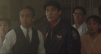 Movie still from “Godzilla vs. Mechagodzilla II” (1993), directed by Kazuki Ômori – A group of men standing next to each other in a room; Medium shot, Over the shoulder angle