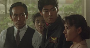 Movie still from “Godzilla vs. Mechagodzilla II” (1993), directed by Kazuki Ômori – A group of people standing next to each other in front of a window; Medium shot, Over the shoulder angle