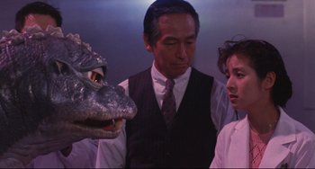 Movie still from “Godzilla vs. Mechagodzilla II” (1993), directed by Kazuki Ômori – A man and two women standing in front of an alligator; Medium shot, Over the shoulder angle