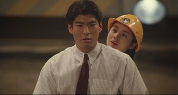 Movie still from “Godzilla vs. Mechagodzilla II” (1993), directed by Kazuki Ômori – A man in a white shirt and a man in a yellow hard hat; Medium shot, Low angle