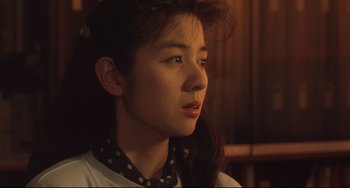 Movie still from “Godzilla vs. Mechagodzilla II” (1993), directed by Kazuki Ômori – A young woman with long dark hair wearing a polka dot neck tie; Close Up shot, Over the shoulder angle