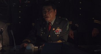Movie still from “Godzilla vs. Mechagodzilla II” (1993), directed by Kazuki Ômori – A man in a military uniform sitting at a table; Medium shot, Low angle