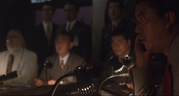 Movie still from “Godzilla vs. Mechagodzilla II” (1993), directed by Kazuki Ômori – A group of men in suits and ties sitting at a table; Close Up shot, Low angle