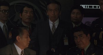 Movie still from “Godzilla vs. Mechagodzilla II” (1993), directed by Kazuki Ômori – A group of people standing in a dark room; Medium shot, High angle