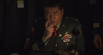 Movie still from “Godzilla vs. Mechagodzilla II” (1993), directed by Kazuki Ômori – A man in military uniform talking on a phone; Medium shot, Low angle