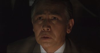 Movie still from “Godzilla vs. Mechagodzilla II” (1993), directed by Kazuki Ômori – An older asian man in a suit and tie; Close Up shot, Low angle